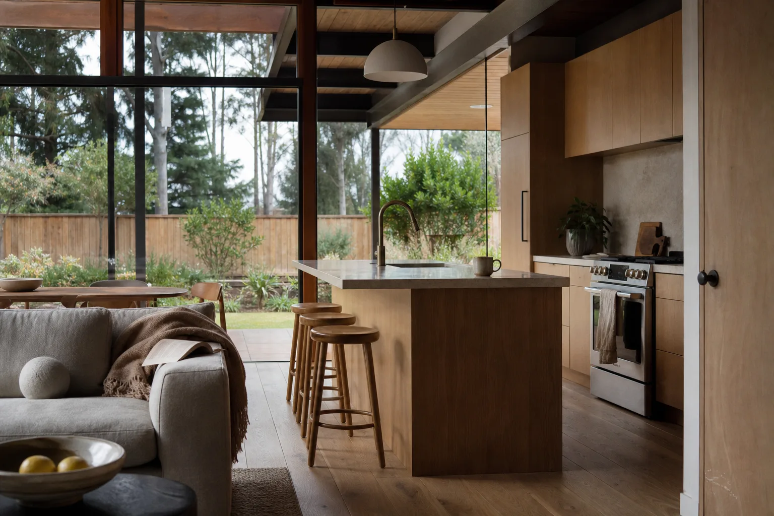 Remodeled Bay Area Eichler-style home with a warm open kitchen and living room, oak cabinetry and floor-to-ceiling glass opening to a modest green backyard