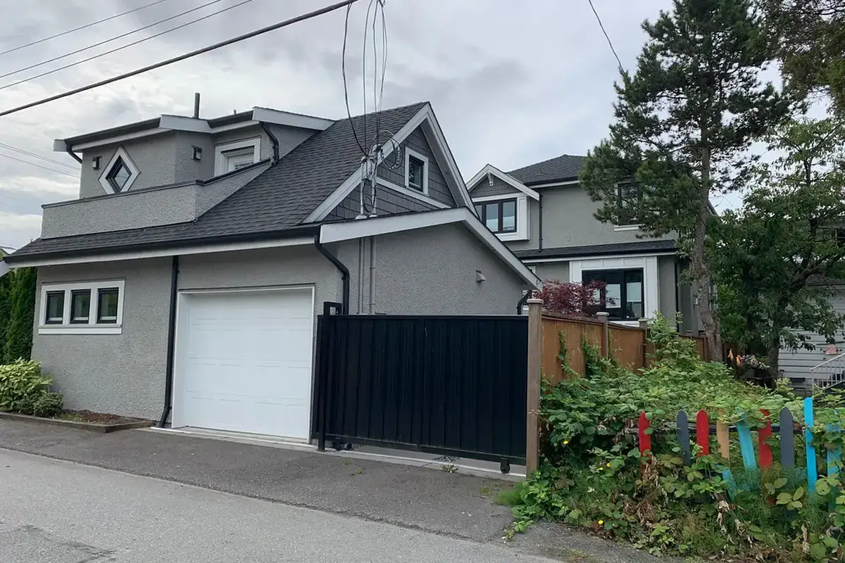 A two-storey laneway house built above a single-car garage, its living space stacked over the parking bay.